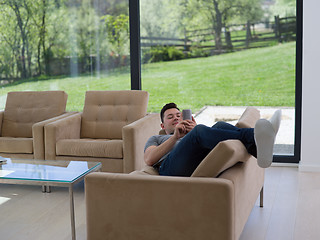 Image showing young man using a mobile phone  at home