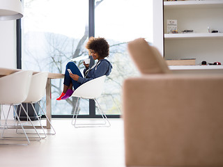 Image showing black woman drinking coffee and using a mobile phone  at home