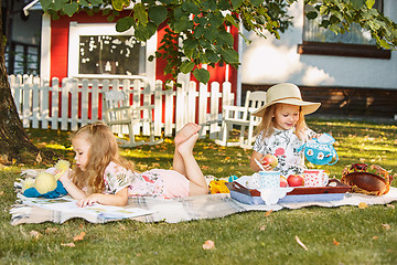 Image showing Cute Little Blond Girls Reading Book Outside on Grass