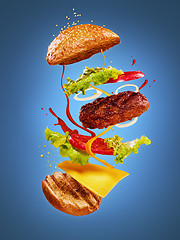 Image showing The hamburger with flying ingredients on blue background