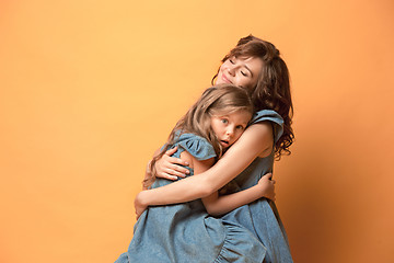 Image showing Pregnant mother with teen daughter. Family studio portrait over brown background