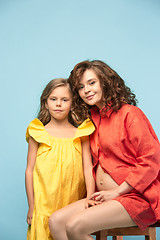 Image showing Pregnant mother with teen daughter. Family studio portrait over blue background