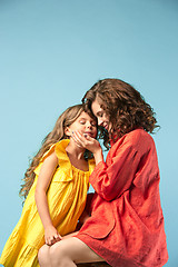 Image showing Pregnant mother with teen daughter. Family studio portrait over blue background