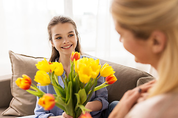 Image showing happy girl giving flowers to mother at home