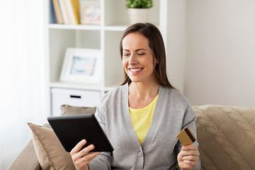 Image showing happy woman with tablet pc and bank card at home