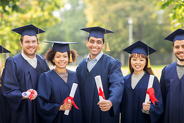 Image showing happy students in mortar boards with diplomas