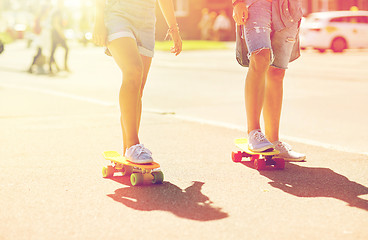 Image showing teenage couple riding skateboards on city street