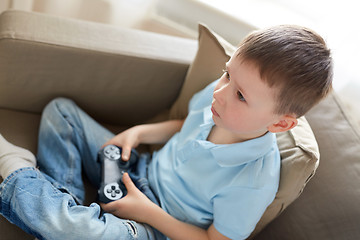 Image showing little boy with gamepad playing video game at home