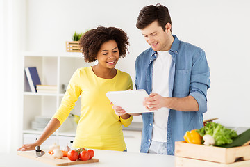 Image showing happy couple with tablet pc cooking food at home