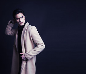 Image showing cool real young man in coat on black background