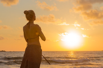 Image showing Woman practicing yoga on sea beach at sunset.