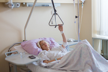 Image showing Bedridden female patient recovering after surgery in hospital care.