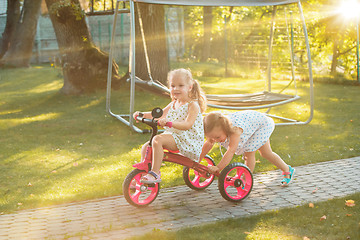 Image showing Cute little blond girls riding a bicycle in summer.