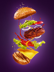 Image showing The hamburger with flying ingredients on lilac background