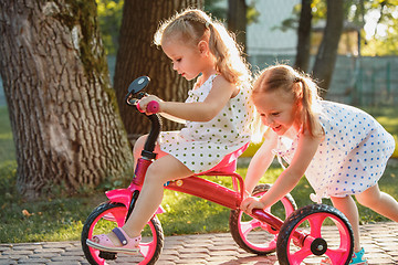 Image showing Cute little blond girls riding a bicycle in summer.