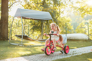 Image showing Cute little blond girls riding a bicycle in summer.