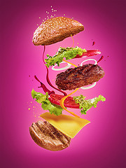 Image showing The hamburger with flying ingredients on lilac background