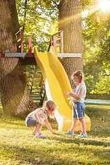 Image showing Happy little girls rolling down the hill on the playground