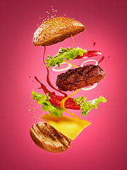 Image showing The hamburger with flying ingredients on rose background