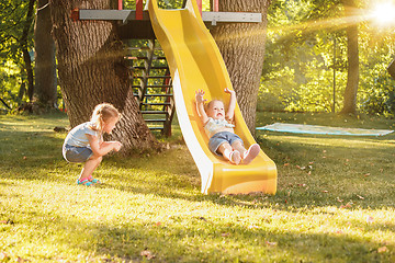 Image showing Happy little girls rolling down the hill on the playground