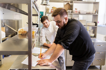 Image showing chef and cook with grocery list at kitchen