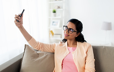 Image showing happy woman taking selfie with smartphone at home