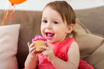 Image showing happy baby girl eating cupcake on birthday party