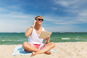 Image showing happy man with tablet pc and headphones on beach