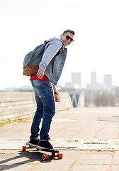 Image showing happy young man or teenage boy riding on longboard