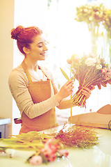 Image showing smiling florist woman making bunch at flower shop