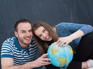 Image showing couple in casual clothing investigating globe