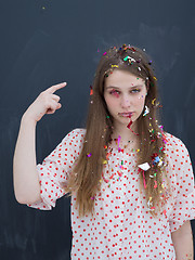 Image showing woman blowing confetti in the air isolated over gray