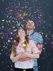 Image showing couple blowing confetti in the air isolated over gray