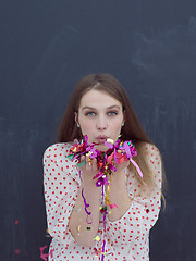 Image showing woman blowing confetti in the air isolated over gray