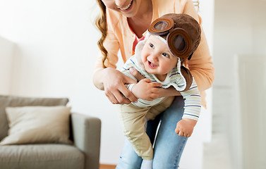 Image showing happy mother with baby wearing pilot hat at home