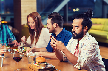 Image showing man with smartphone and friends at restaurant