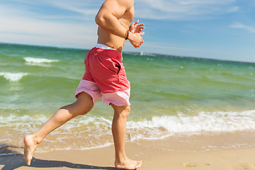 Image showing happy man running along summer beach