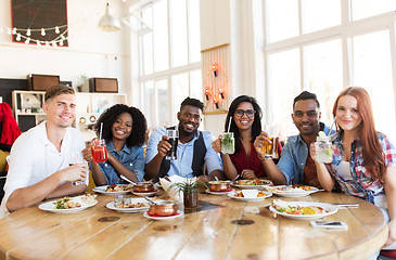 Image showing happy friends eating and drinking at restaurant