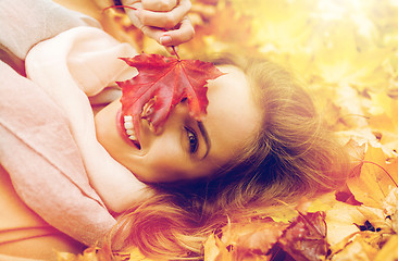 Image showing beautiful happy woman lying on autumn leaves