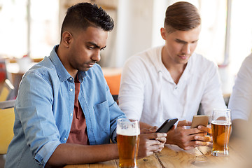 Image showing male friends with smartphone drinking beer at bar