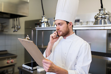 Image showing chef cook calling on smartphone at restaurant kitchen