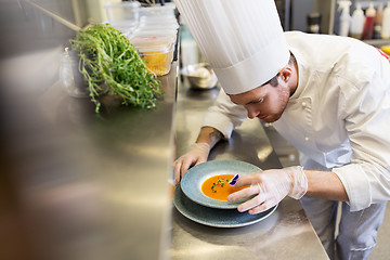 Image showing male chef decorating dish with pansy flower