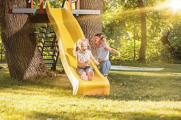 Image showing Happy little girls rolling down the hill on the playground