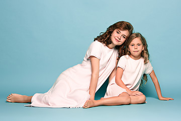 Image showing Pregnant mother with teen daughter. Family studio portrait over blue background
