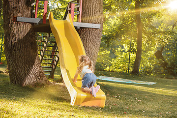 Image showing Happy little girl rolling down the hill on the playground