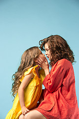 Image showing Pregnant mother with teen daughter. Family studio portrait over blue background