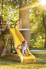 Image showing Happy little girl rolling down the hill on the playground