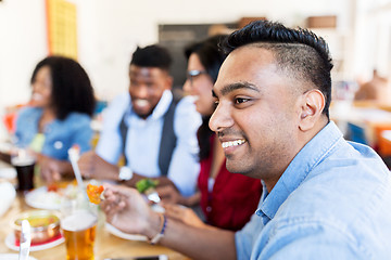 Image showing happy friends eating and talking at restaurant