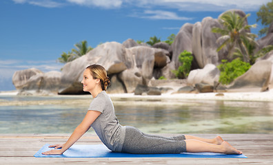 Image showing woman doing yoga in dog pose on beach