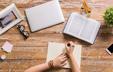 Image showing hands with book writing to notebook at table